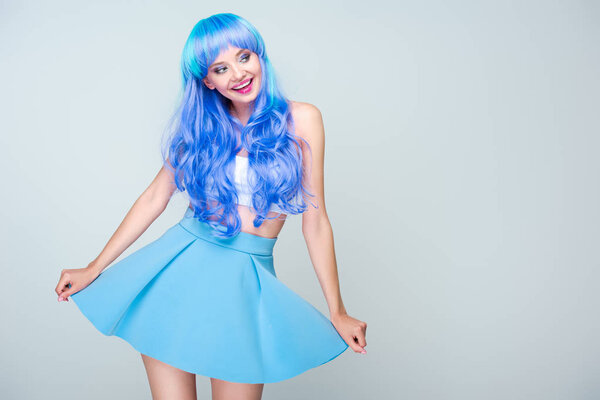 smiling young woman with bright blue hair and skirt isolated on grey