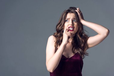 frightened young woman in stylish red dress looking away isolated on grey clipart