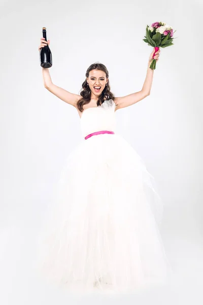 シャンパンのボトルと白で隔離ブライダル ブーケとウェディング ドレスの若い花嫁を祝う  — 無料ストックフォト