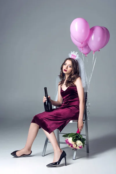 Depressed future bride in veil for bachelorette party sitting on chair with champagne and flowers and looking at camera after party on grey — Stock Image Depressed Future Bride Veil Bachelorette Party Sitting Chair Champagne Flowers Royalty Free Stock Photos