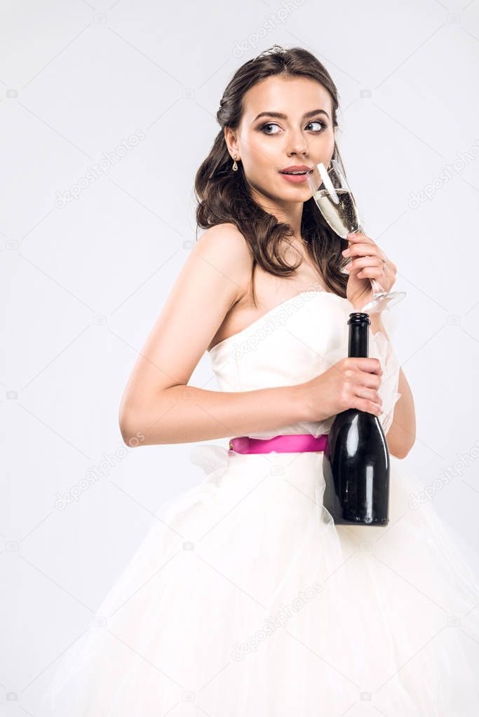 attractive young bride in wedding dress with bottle and glass of champagne isolated on white