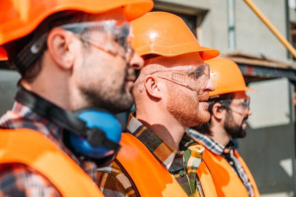 side view of group of equipped builders standing at construction site