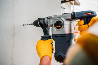 cropped shot of builder using power drill at construction site clipart