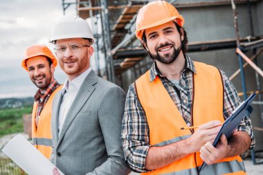 inşaatçılar ve mimar blueprint ve kameraya bakarak Pano