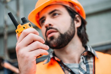 yakın çekim portre Builder koruyucu kask ve inşaat alanında walkie talkie kullanarak yelek