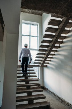 rear view of architect going upstairs inside of building house clipart