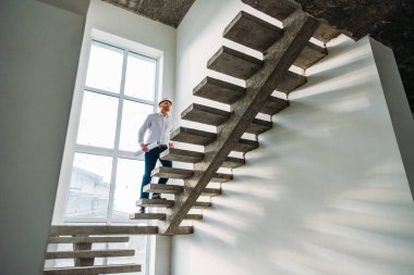 handsome architect in white shirt going upstairs inside of building house clipart