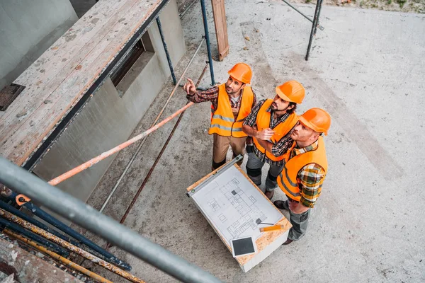 Vista Alto Angolo Gruppo Costruttori Discutendo Piano Costruzione Cantiere Guardando — Foto Stock