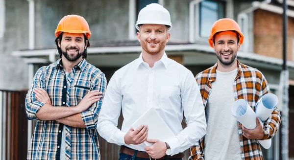 Gruppo Architetti Successo Cappelli Duri Guardando Fotocamera Fronte Alla Casa — Foto Stock