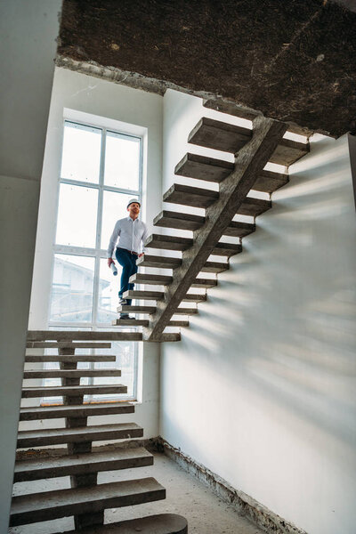 handsome architect going upstairs inside of building house