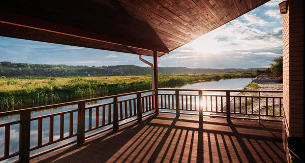 wide shot of beautiful sunset over river from wooden terrace
