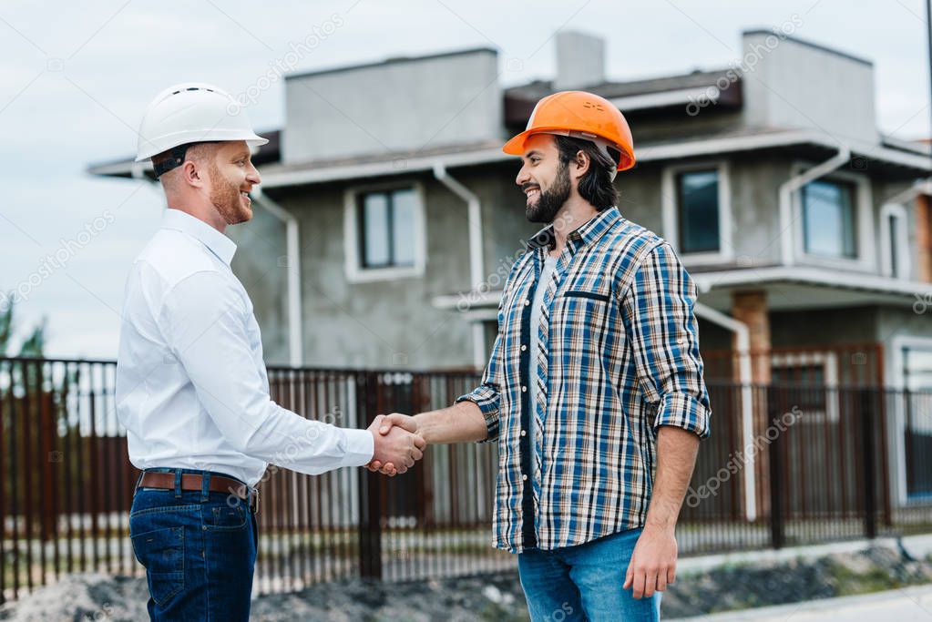 handsome architects shaking hands at construction site