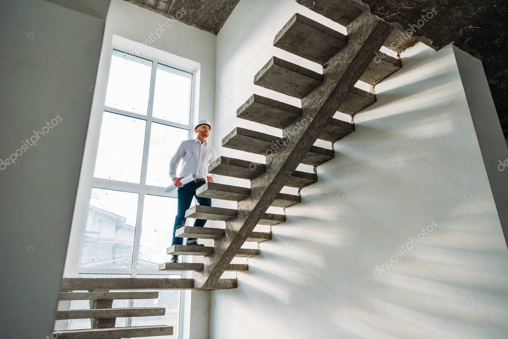 handsome architect in white shirt going upstairs inside of building house