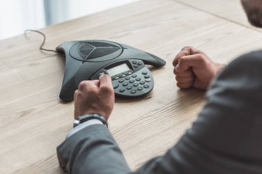 konferans telefon önünde oturan ve ofiste yumruk yapma kızgın işadamı kadeh kırpılmış