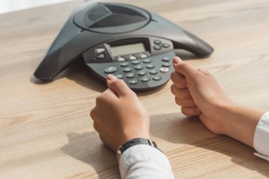 konferans telefon önünde masada oturan ve yumruk yapma işkadını kırpılmış atış