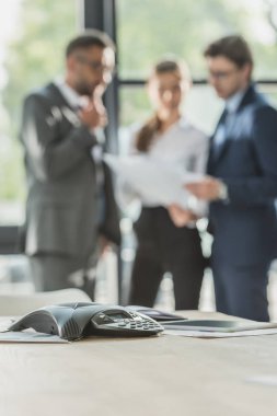birlikte modern ofis, arka planda çalışan bulanık iş adamları ile konferans telefon yakın çekim vurdu