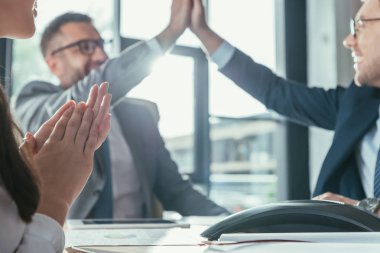 successful business people giving high five during meeting at modern office clipart