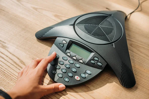 stock image cropped shot of businesswoman with pink nails pushing button of speakerphone at workplace