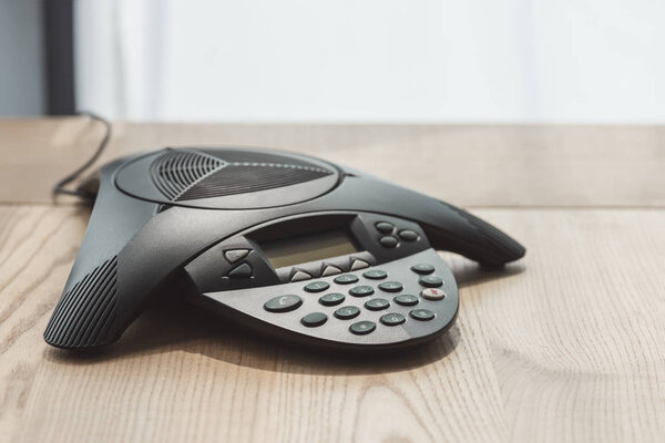 close-up shot of modern conference phone on wooden table at office