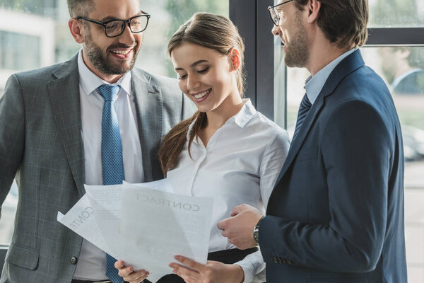счастливые молодые бизнесмены вместе обсуждают документы в офисе
