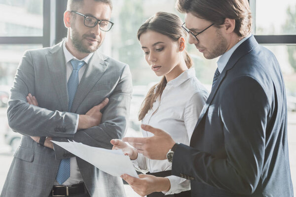 успешные молодые бизнесмены вместе обсуждают документы в офисе
