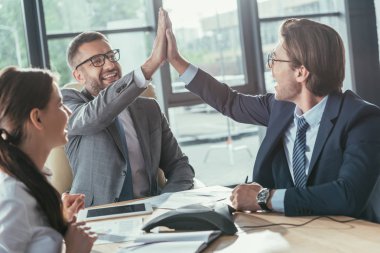 happy business people giving high five during meeting at modern office