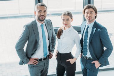 Grup Genç iş gülümseyen insanlar modern ofiste ayakta ve kameraya bakıyor