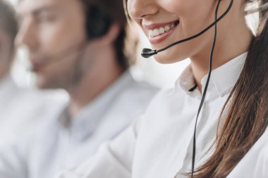 cropped shot of smiling young call center manageress working with colleagues
