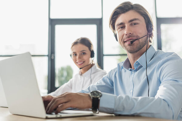male and female call center managers working together at modern office and looking at camera