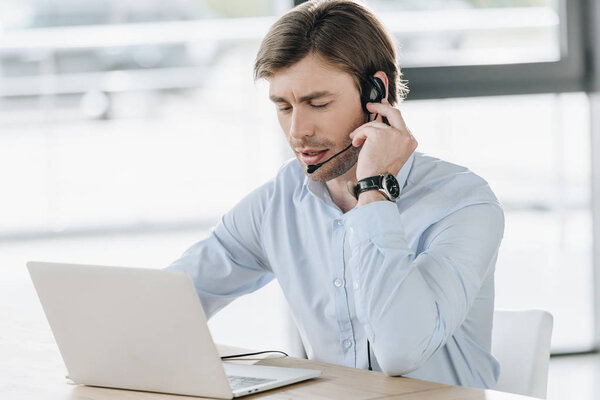 confident call center worker with laptop sitting at workplace