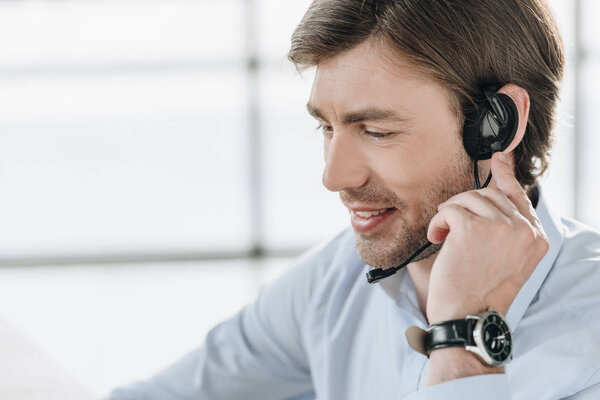 smiling support hotline worker in headphones with microphone at work