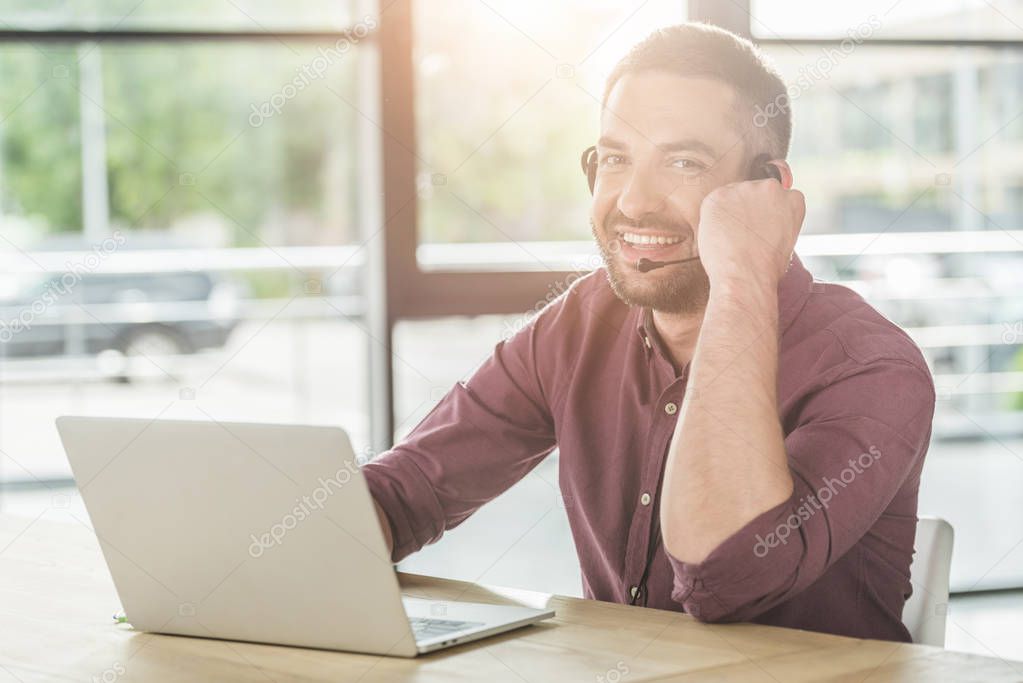 handsome young call center worker working at modern office and looking at camera