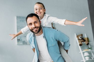 Baba piggybacking ve evde kameraya bakarak mutlu kızı