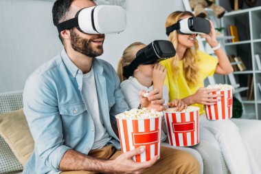Genç aile içinde sanal gerçeklik kulaklıklar kova patlamış mısır ile film izlerken heyecanlı