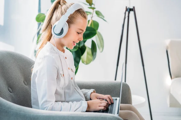 Side View Smiling Little Child Headphones Using Laptop While Sitting — Free Stock Photo