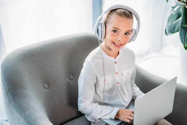 Smiling Little Child Headphones Using Laptop While Sitting Armchair Looking — Free Stock Photo