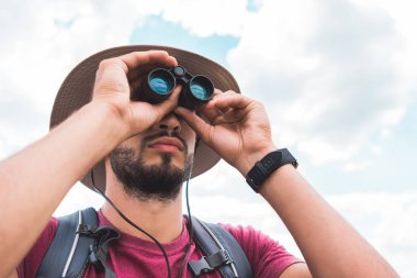 handsome male tourist in hat looking in binoculars clipart