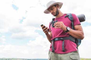 sırt çantası ve smartphone kullanarak dürbün ile erkek gezgin 
