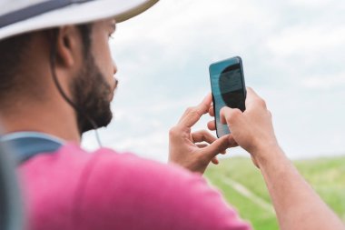 çayır üzerinde Smartphone cep telefonu ile fotoğraf çekme sırt çantası ile erkek turist