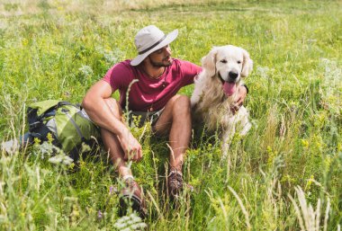 Gezgin ile golden retriever köpek yeşil çayır üzerinde oturan şapkalı