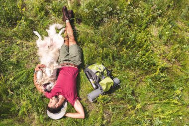 üstten görünüm turist ve köpek sırt çantası ile yeşil çim üzerinde yalan