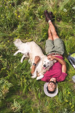 üstten görünüm turist ve golden retriever köpek yeşil çim üzerinde yalan  