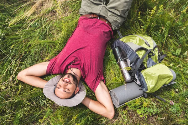 在草地上悠闲的年轻游客的背包 旅游垫和热水瓶的顶部视图 — 图库照片