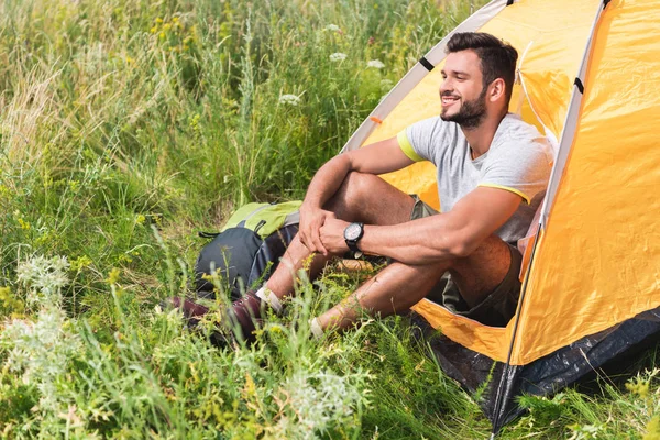 愉快的旅行者与背包坐在黄色帐篷在草甸 — 图库照片