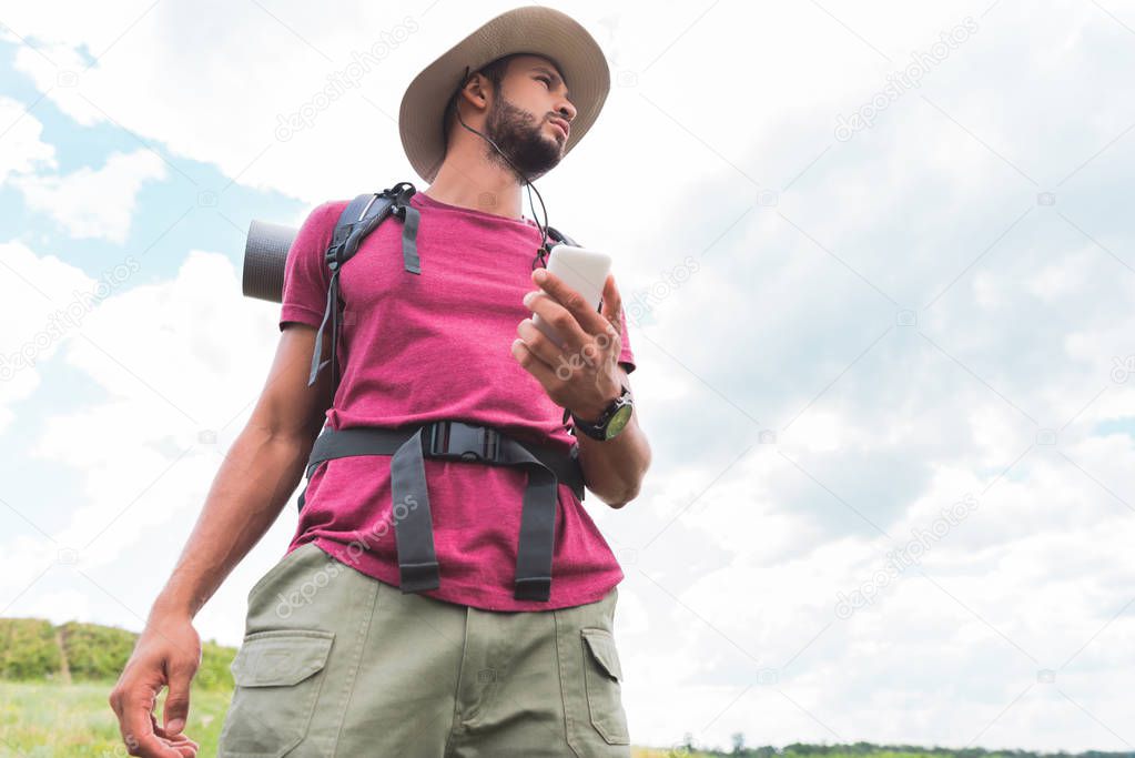 bottom view of handsome traveler with backpack using smartphone 