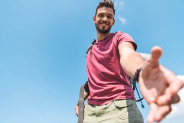 El, mavi gökyüzü arka plan üzerinde uzanan yakışıklı genç turist alttan görünüm