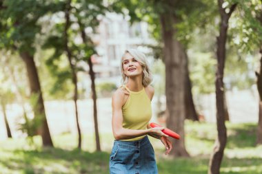 attractive blonde girl throwing frisbee disk in park  clipart