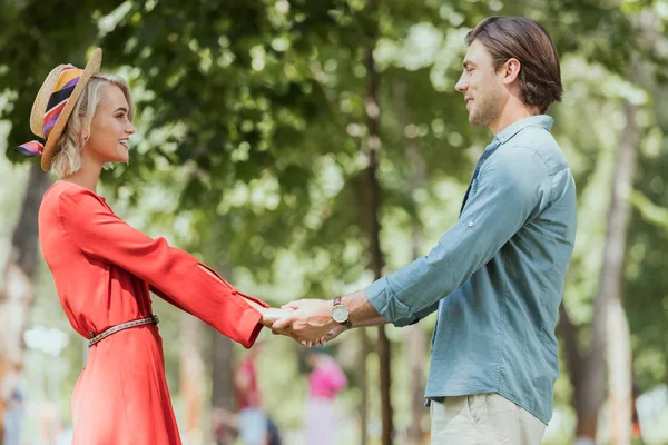 公園で手をカップルの持株を笑顔の側面図 — ストック写真