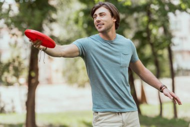 handsome man throwing frisbee disk in park clipart