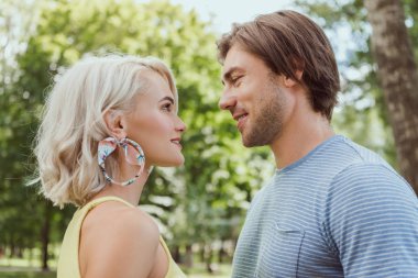 side view of couple looking at each other in park clipart